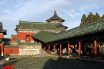 aka The Temple of Heaven. View of the red and green rooved architecture within the complex with people sitting on a fence