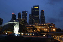 Merlion statue spouting water illuminated against a night time city skyline