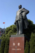 The Bund. Statue of Mao against a backdrop of formal bushes and a flag fly from the roof of the building in the background