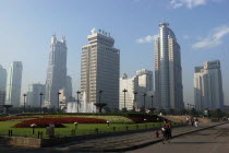 Modern city skyline with flowerbeds and fountain in the foreground with passing cyclist