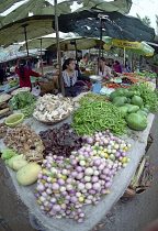 Wide angled view of female vendor selling fresh fruit and vegetable produce at the market