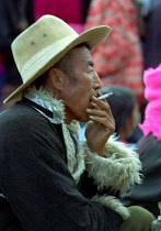 Man in a hat and fur rimmed coat smoking a cigarette