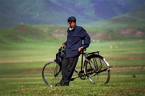 Weary traveller leaning against bicycle in green landscape