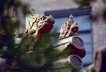 Close up of decorative roof carvings in the ancient grounds where Confucius practiced seen through leaves Qufu