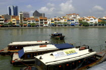 Three moored boats on Singapore River with city architecture on the opposite bank