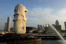 Merlion statue spouting water over Singapore River in evening light with the city skyline beyond