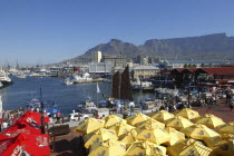 View over the waterfront area with brightly coloured umbrellas in the foreground and Table Mountain in the background