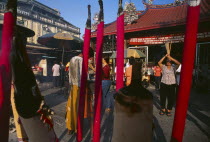 Goddess of Mercy Temple  also known as Kuan Yin Teng.  Exterior with worshippers and large  pink  burning incense sticks.