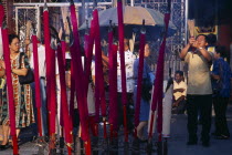 Goddess of Mercy Temple  also known as Kuan Yin Teng.  Exterior with worshippers and large  pink  burning incense sticks.