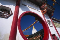 Ban Po  the Pagoda of a Thousand Buddhas and string of red and yellow coloured Chinese lanterns framed by circular opening in red and white painted wall.