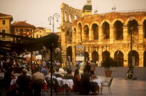 Piazza Bra.  Busy cafe with people eating and drinking at outside tables in front of the Arena.