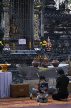 Wat Chettawan on Tha Phae Road.  Young woman and girl kneeling with incense in front of stone niche with seated Buddha and altar with burning incense.Asian Kids Prathet Thai Raja Anachakra Thai Relig...