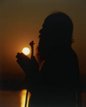 Silhouette of Holy Man praying on the banks of the River Ganges at sunset