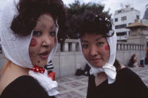 Harajuku District. Portrait of two young teenage girls wearing theatrical face makeup and white headscarfs