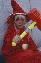 Harajuku District. Portrait of young teenage girl wearing a red and black spotted outfit holding a toy hammer