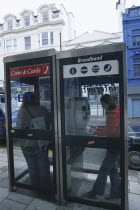 Communications, Phone Box, Young woman using a public BT Internet phone booth.