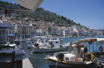 Fishing boats moored in harbour with waterfront buildings behind.