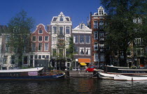 Moored barge on the side of the Oude Schans canal lined with traditional architecture