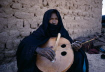 Tuareg woman playing an Imzad.  A traditional instrument consisting of a goatskin covered gourd or wooden resonator played with a curved bow and horsehair string.