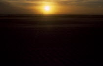 Clearwater beach at sunset with bright orange sun over the sea.