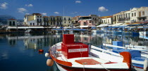 Venetian Port.  Colourful red  white and blue painted boats moored in harbour overlooked by hotels  bars and restaurants.