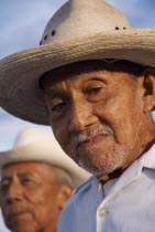 Two smiling  elderly men in hats  head and shoulders portraits one only part seen in background.