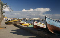 View of fishing boats pulled ashore with view of the harbour and Fort Qaitbey  in the distance.