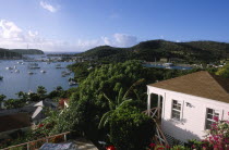 Ordnance Bay.  View over bay with moored yachts and tree covered coastline with part seen white painted house in the foreground.