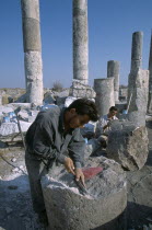 Historical site of Roman military headquarters above the village of Qalaat Mudiq.  Restoration workers with columns and fallen masonry behind.