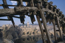 Wooden norias or waterwheels on the Orontes river.  Part view of wheel section in the foreground framing the Al-Nuri Mosque dating from 1172 and built of limestone and basalt.