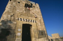 The Citadel. Monumental gateway  facade of crenellated tower with arrow slits and decorated with a horizontal calligraphic band above the doorway.