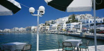 Hora.  View from waterside eating area under black and white sun umbrellas  towards white painted town buildings.