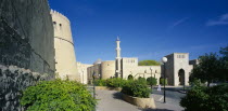 Town centre with crenellated walls surrounding quiet  open  paved area with raised flower beds and trees.