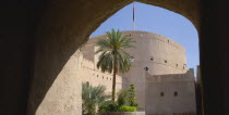 Nizwa Fort  built in the mid seventeenth century.  Exterior view framed by archway in shadow.