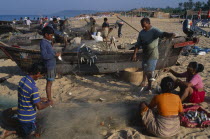 People inc. family group working on the beach sorting fishing nets