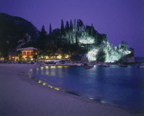 View along Krioneri Beach to restaurant and rocky headland illuminated at night