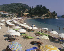 Krioneri Beach  view along busy beach with umbrellas and sun loungers to rocky headland