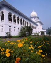 Supreme Court Building exterior facade with ornate white arches and orange flowers in foreground.