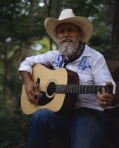 Bearded cowboy on the Mayan Ranch playing acoustic guitar