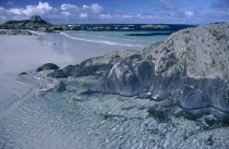 White sandy beach with rocks and clear blue water