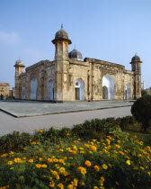 Lalbagh Fort.  Exterior facade with paving and orange flowers in the foreground.