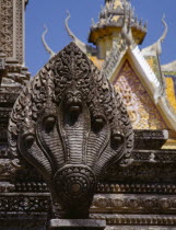 Stone carving of naga on temple stupa with roof of Silver Pagoda part seen behind.