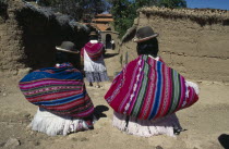 Yumani Villagers carrying brightly coloured bundles over their shoulders. Colored Colored