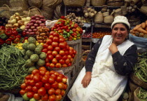 Fruit and vegetable stall and smiling woman vendor.