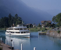 White passenger ferry nearing quay with misty wooded mountains in the distance