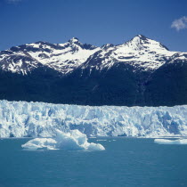 Moreno Glacier below snow capped mountains with icebergs on Lago Argentian in typical Patagonian landscape