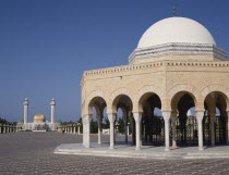 Bourguiba Mausoleum in distance beyond an arched portico with a white dome