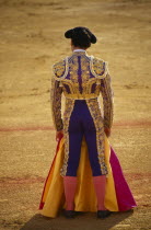 Matador in bull ring with cape covering his legs Andalusia