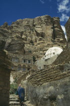 Houses in hills  one white domed. Two women walking up steps