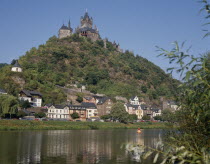 Hilltop castle with conical towers overlooking houses beside the Mosel River